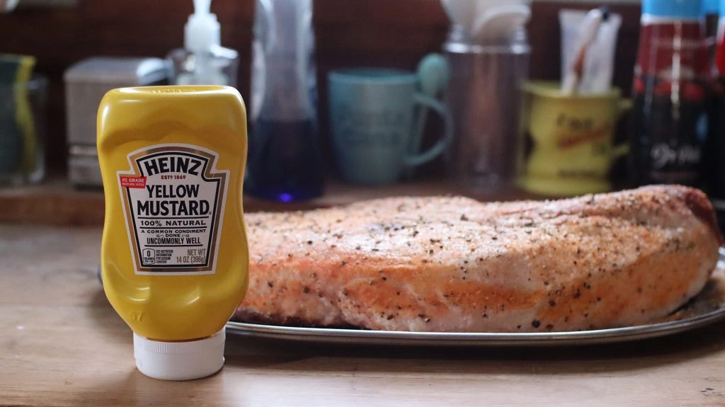 a bottle of heinz yellow mustard next to a brisket with no binder