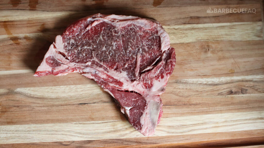 raw t-bone steak on cutting board