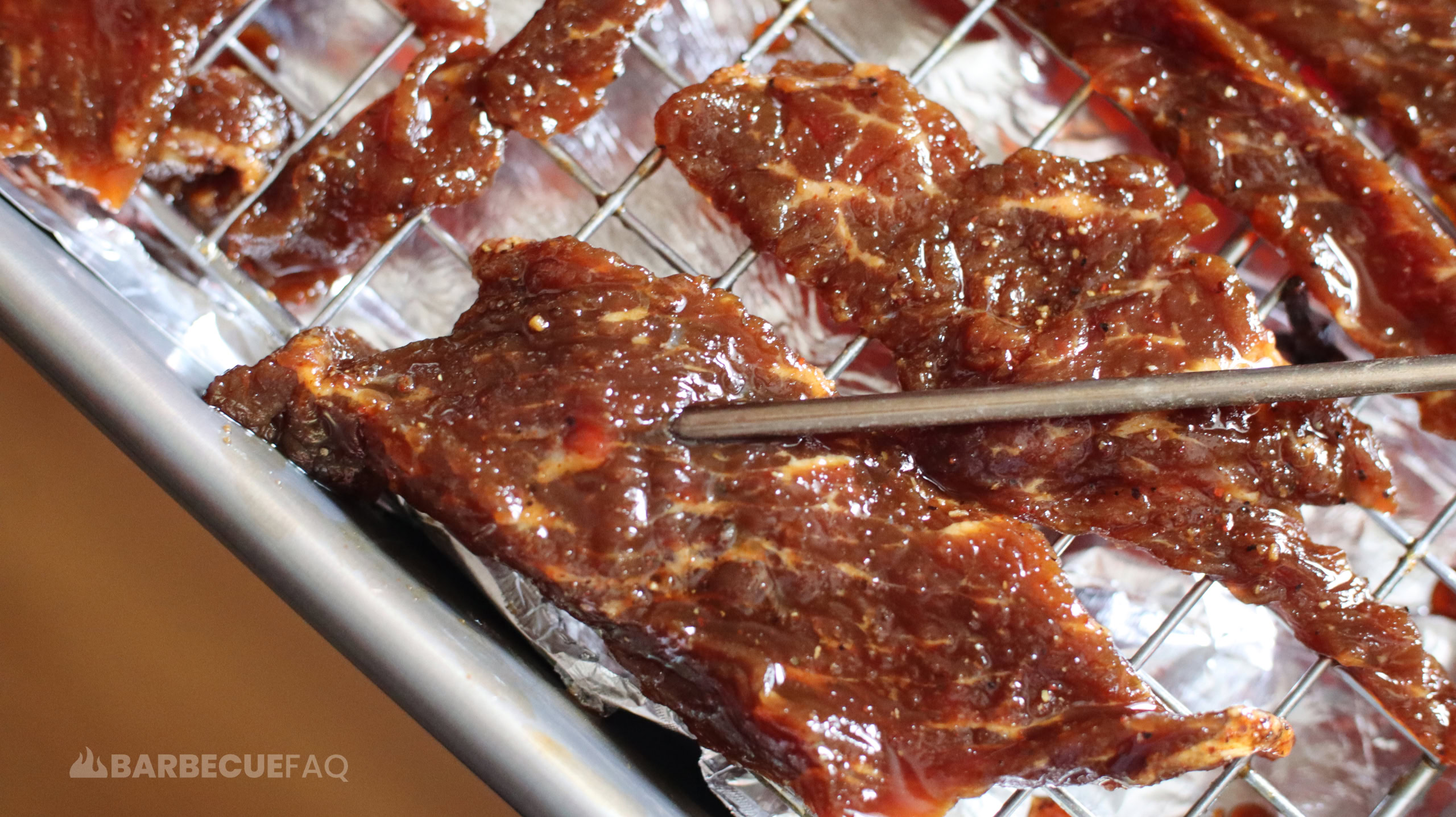 probing thick piece of jerky meat to tell when beef jerky is done