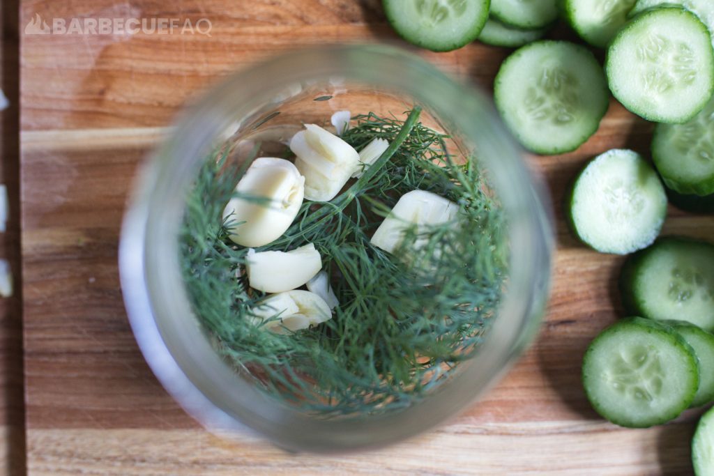 dill and crushed garlic at the bottom of the jar